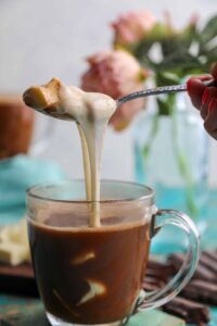 Colombian chocolate with cheese with melted cheese being lifted from the cup
